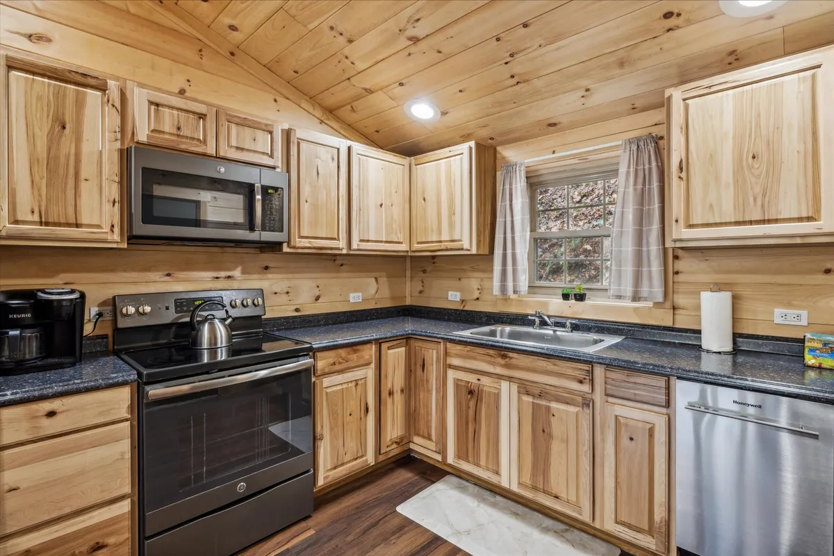 A kitchen with wooden cabinetry, stainless steel appliances, a kitchen sink, and a window that offers a view. The layout and features cater to both cooking and entertaining, with enough space for movement and gathering.