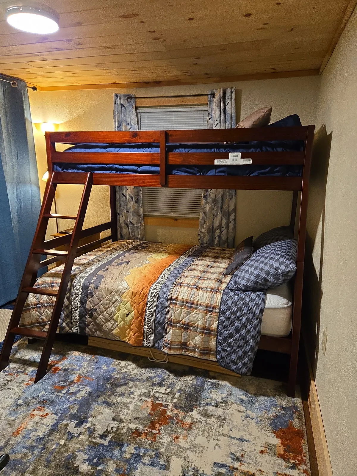 A playful bunk bed area adorned with a colorful quilt and a rug, inviting kids or families to enjoy bedtime stories, play, or movie nights together. The setup is ideal for building blanket forts or creating a cozy movie-watching nook.