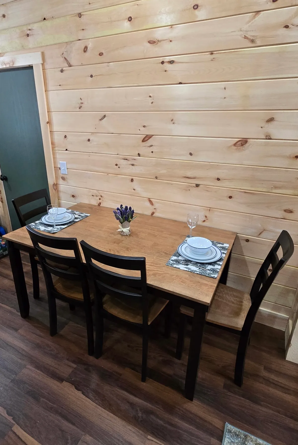 A cozy dining area with a wooden dining table, neatly arranged place settings, a lavender centerpiece, and comfortable dining chairs. The setting is intimate, ideal for romantic dinners or family gatherings.